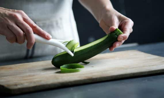 person pealing green cucumber inside room